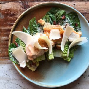 Sałatka cezar z grillowanym kurczakiem, sałatą rzymską, chipsami z boczku, grzankami